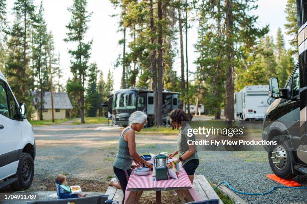 active senior woman preparing meal outdoors while on camping trip with her multi-generation family - motor home stock pictures, royalty-free photos & images