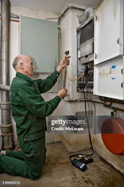 Male heating and sanitary technician testing and adjusting a gas heater.