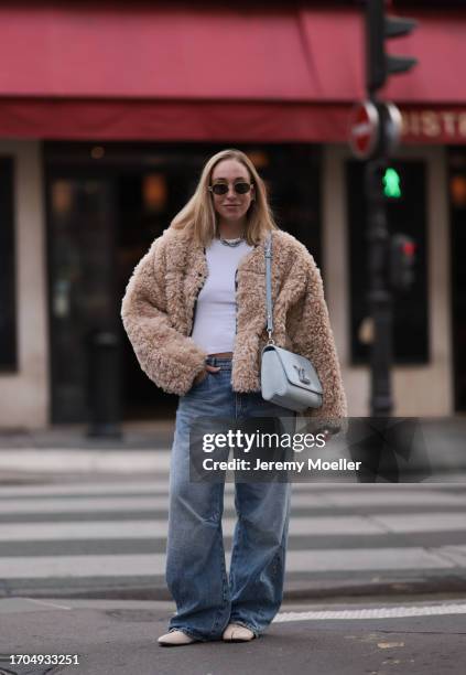 Sonia Lyson is seen wearing sunglasses with golden frame from Celine, a twisted silver necklace from Zara, a fluffy beige jacket from Stand Studio,...