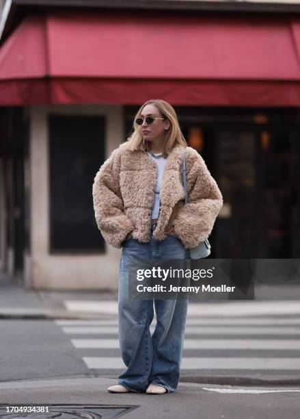 Sonia Lyson is seen wearing sunglasses with golden frame from Celine, a twisted silver necklace from Zara, a fluffy beige jacket from Stand Studio,...