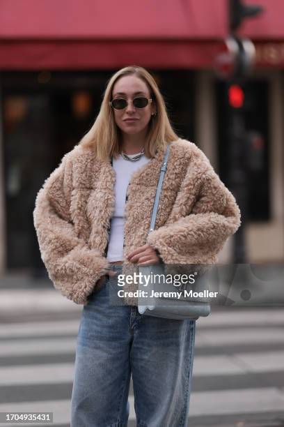 Sonia Lyson is seen wearing sunglasses with golden frame from Celine, a twisted silver necklace from Zara, a fluffy beige jacket from Stand Studio,...