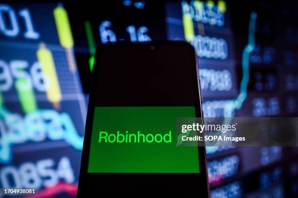 In this photo illustration, a RobinHood logo is displayed on a smartphone with stock market percentages on the background.