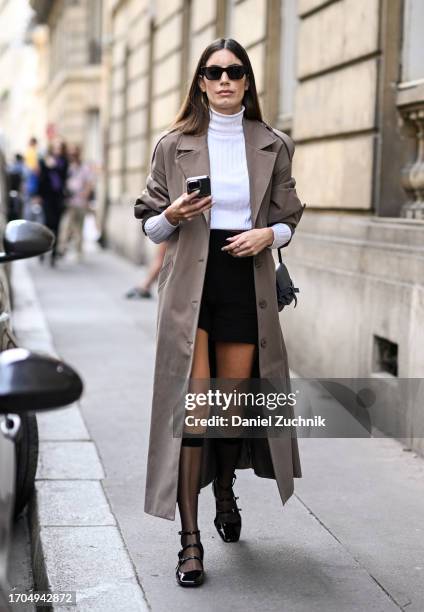 Guest is seen wearing a tan trench coat, white turtle neck, black skirt and black shoes with sheer socks and black sunglasses outside the Marni show...