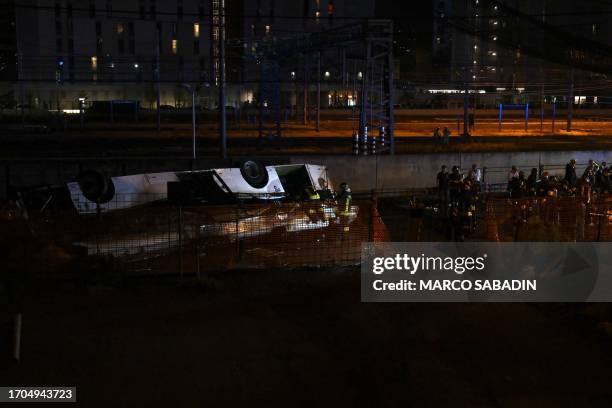 Firefighters work on the site of a bus accident on October 03, 2023 in Mestre, near Venice. At least 20 people were killed Tuesday when a bus plunged...