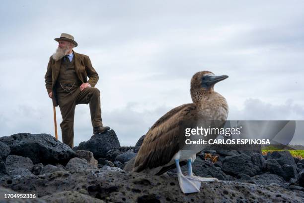 Kenneth Noll, in the costume of the English naturalist, geologist, and biologist Charles Robert Darwin, poses for a picture next to a blue-footed...