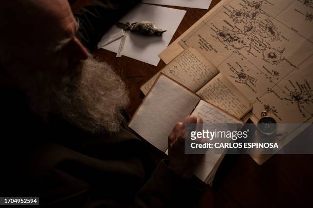 Kenneth Noll, in the costume of the English naturalist, geologist, and biologist Charles Robert Darwin, writes inside a library during an interview...