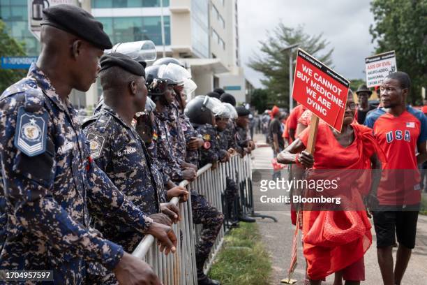 Police officers stand guard as protesters march past during the 'Occupy Bank of Ghana' protest in Accra, Ghana, on Tuesday, Oct. 3, 2023. The...