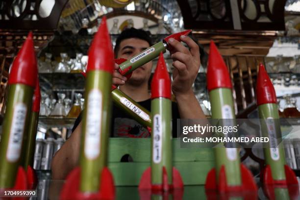 An employee handles bottles of perfume shaped like locally made Qassam rockets, sold in a shop in Gaza City on October 4, 2023.