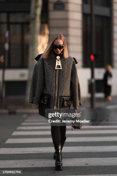 Sonia Lyson is seen wearing large black sunglasses with golden detail from Louis Vuitton; several golden hoop earrings; a wool mix coat with padded...