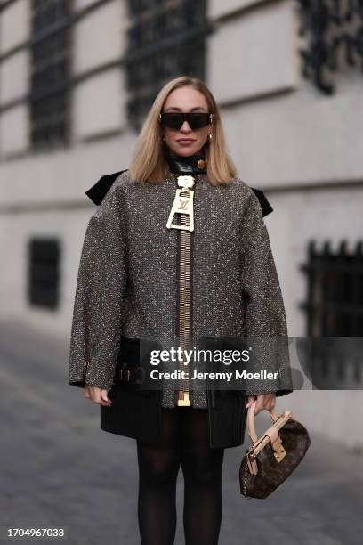 Sonia Lyson is seen wearing large black sunglasses with golden detail from Louis Vuitton; several golden hoop earrings; a wool mix coat with padded...