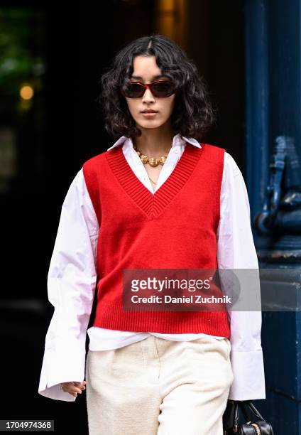 Guest is seen wearing a white button shirt, red sweater vest, cream oversized pants, black sunglasses and a black and gold Miu Miu bag outside the...