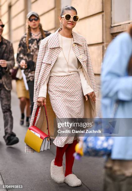 Guest is seen wearing a plaid Marni coat and skirt, cream sweater, red stockings, white faux fur shoes and Marni color block bag outside the Marni...