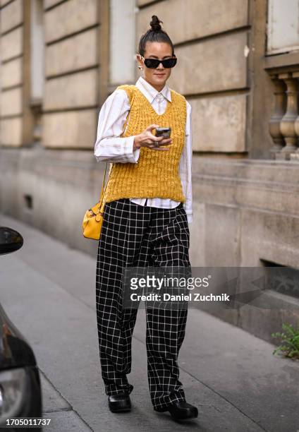 Guest is seen wearing a white shirt, yellow vest, brown and white pants, black sunglasses and a yellow bag outside the Marni show during the...
