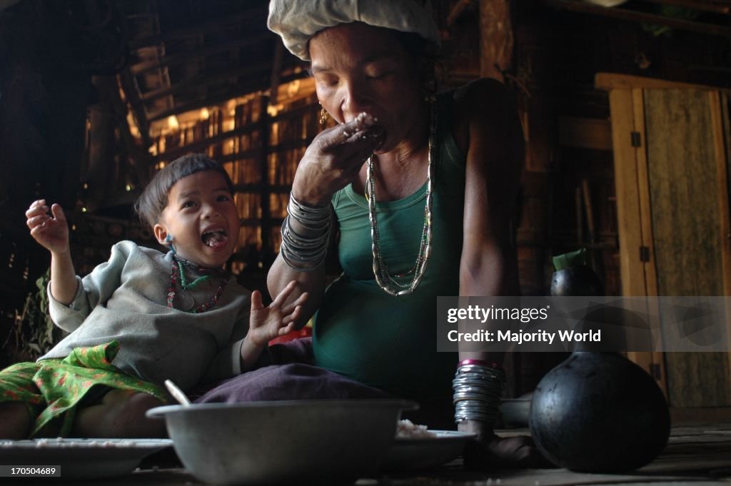 A pregnant Murong tribal woman eating food in her house