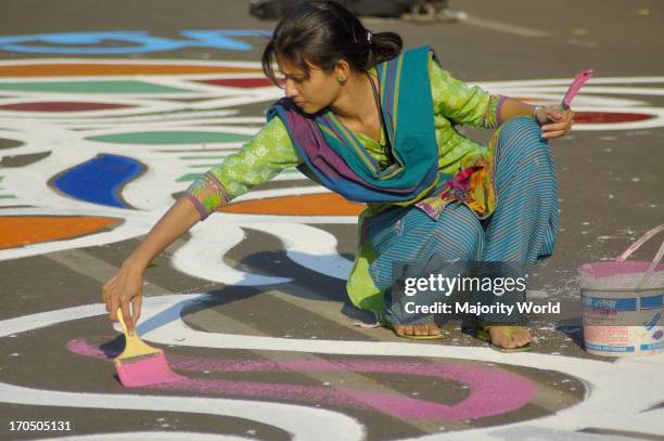 Students from the Fine Arts Institute of Dhaka University paints floral motifs on the road infront of Central Shahid Minar, a monument for the...