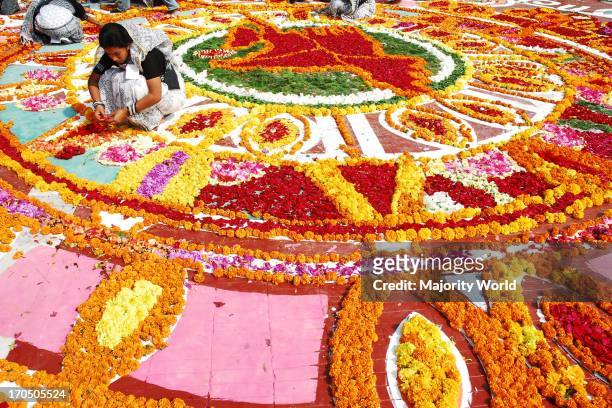 Girls decorate flowers at Central Shahid Minar. Central Shahid Minar at Dhaka covered with flowers on the eve of International Mother Language Day....