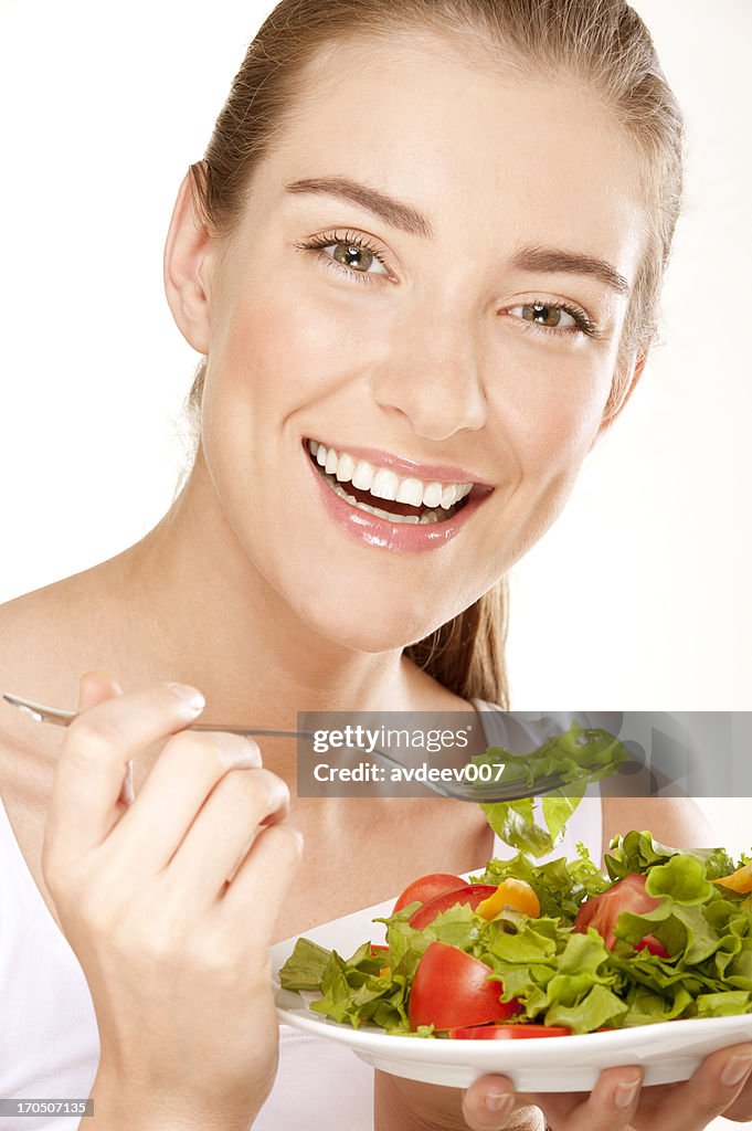 Smiling young woman eats salad
