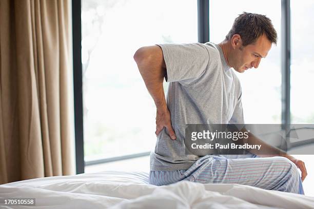 男性に座って背中のベッド - 腰痛 ストックフォトと画像