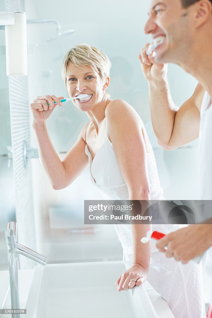 Casal escovar os dentes em casa de banho