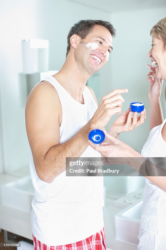 Woman putting face cream on husbands face