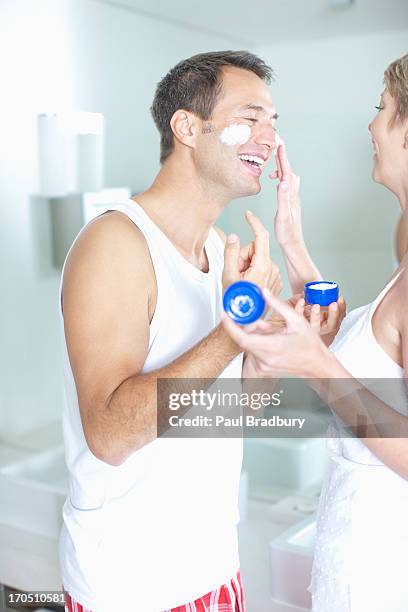 woman putting face cream on husbands face - naughty wife stock pictures, royalty-free photos & images