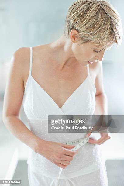 woman measuring waistline - smiling woman waist up stock pictures, royalty-free photos & images