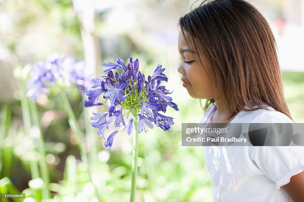 Girl smelling flower outdoors, portrait