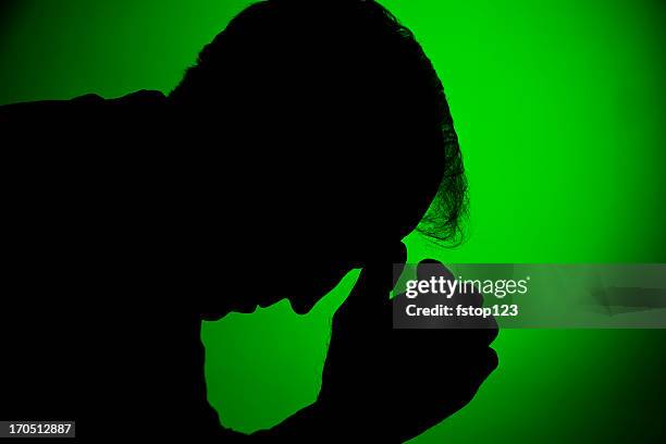 depressed man in silhouette on green - head in hands silhouette stock pictures, royalty-free photos & images