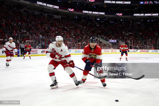 Jaccob Slavin of the Carolina Hurricanes and Mike Reilly of the Florida Panthers skate for the puck during the third period of their game at PNC...