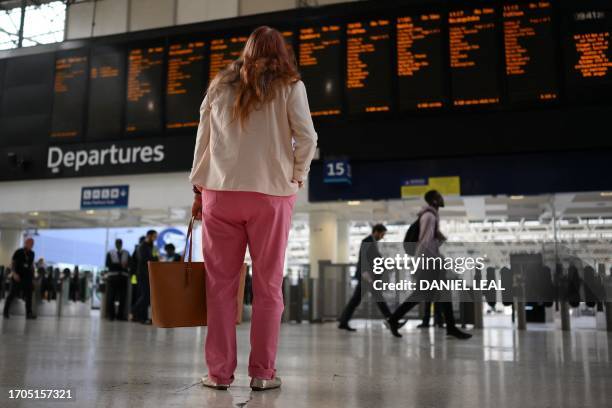 Commuter looks at a departures board at Waterloo Station in London on October 4, 2023 as train drivers strike over pay. Workers on the London...