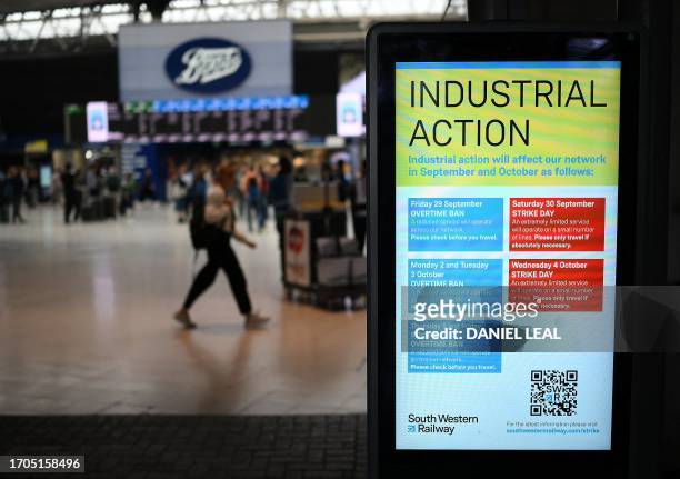 Commuters walk past an announcement board informing people of strike details at Waterloo Station in London on October 4, 2023 as train drivers strike...