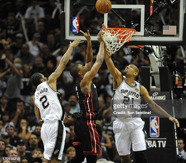 The Miami Heat's Chris Bosh, middle, has his shot blcked by Tim Duncan of the San Antonio Spurs during the third quarter of Game 4 of the NBA Finals...