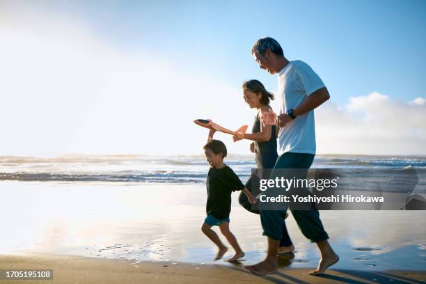 toddler running on beach with toy airplane - família de duas gerações imagens e fotografias de stock