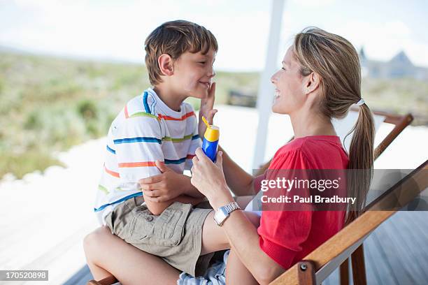 mother putting sunscreen on boy - putting lotion stock pictures, royalty-free photos & images