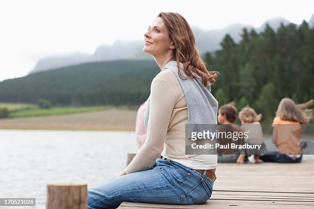 familia sentada en el muelle junto al lago - 40 44 años fotografías e imágenes de stock