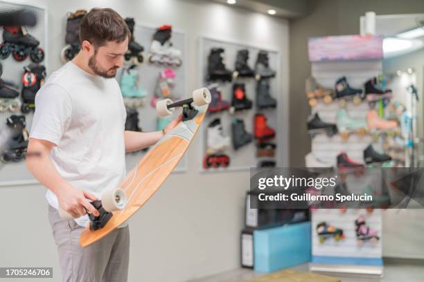 man checking a skateboard to buy it - skateboard shop stock pictures, royalty-free photos & images