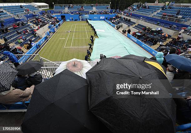 Groundstaff pull on the covers on The Ann Jones Centre Court as the rain comes down during the match between Sorana Cirstea of Romania and Donna...