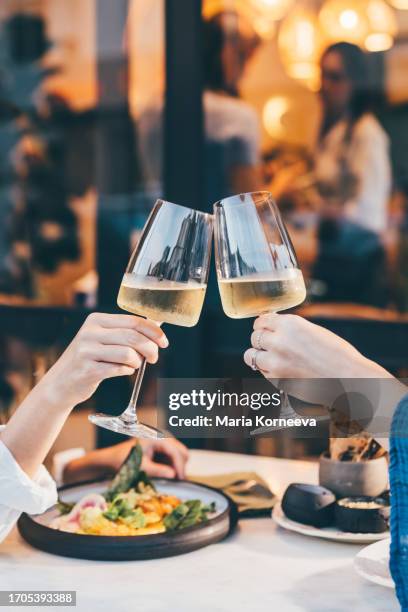 girlfriends toasting with white wine in restaurant. - mesa-para-dos fotografías e imágenes de stock