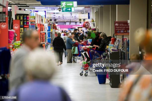 Customers do their shopping in a Carrefour supermarket, on June 14, 2013 in Sainte-Geneviève-des-Bois, outside Paris. Installed in...