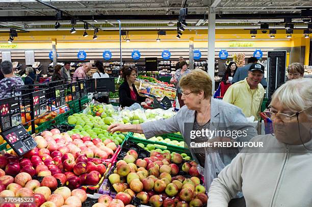Customers look at apples at the fruits and vegetables section of a Carrefour supermarket, on June 14, 2013 in Sainte-Geneviève-des-Bois, outside...