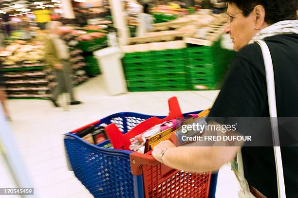 Customers pushes a shopping cart in a Carrefour supermarket, on June 14, 2013 in Sainte-Geneviève-des-Bois, outside Paris. Installed in...