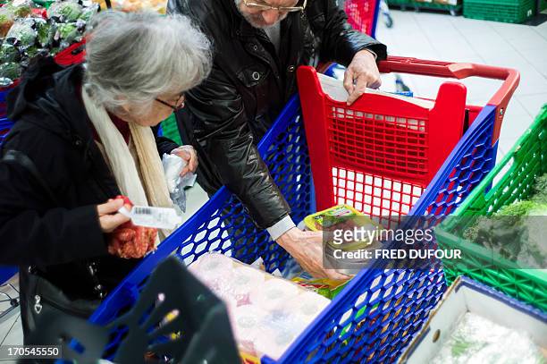 Customers put goods in their shopping cart in a Carrefour supermarket, on June 14, 2013 in Sainte-Geneviève-des-Bois, outside Paris. Installed in...