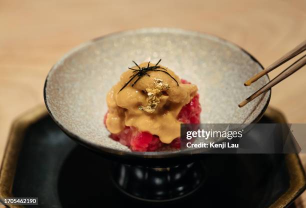 close up of a bowl of freshly served sea ​​urchin and raw beef on the table in a japanese restaurant. asian cuisine and food culture. eating out lifestyle. - oursin de mer photos et images de collection