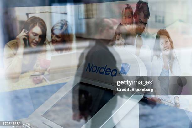 Pedestrian is reflected in the window of a Nordea Bank Polska SA bank branch in Wroclaw, Poland, on Friday, June 14, 2013. PKO Bank Polski SA,...