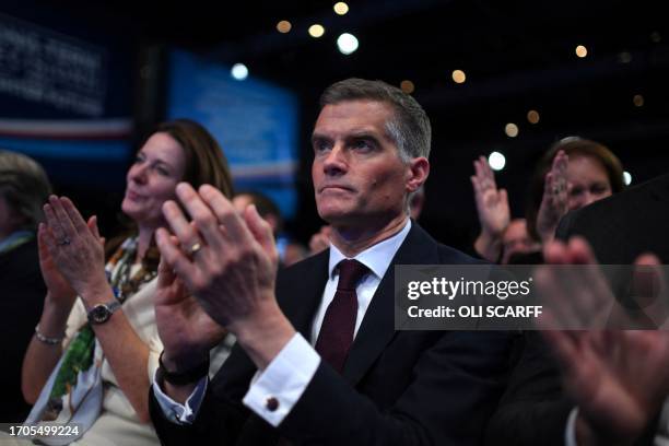 Britain's Transport Secretary Mark Harper listens to Britain's Prime Minister Rishi Sunak at the annual Conservative Party Conference in Manchester,...