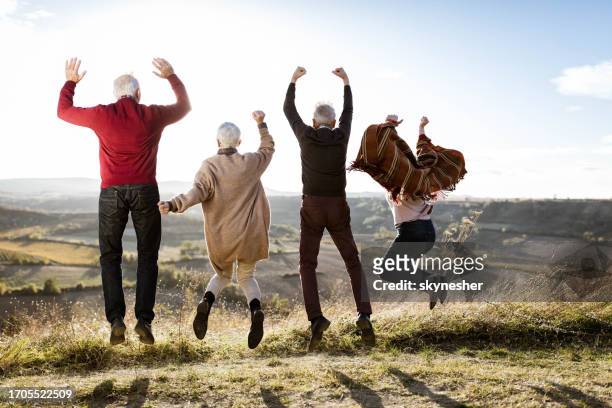 rückansicht von verspielten senioren, die auf einen hügel springen. - old couple jumping stock-fotos und bilder
