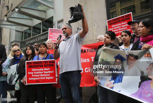 Immigration reform advocate Ravi Ragbir holds up a pair of shoes symbolizing a deported father during a demonstration, organized by the New York...