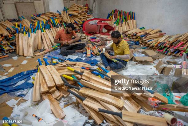 Kashmiri craftsmen enhance the beauty of cricket bats as they affix stickers before packaging in a bat factory on October 3, 2023 in Halmullah, 50...