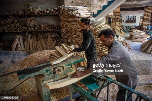Workers shape cricket bats using specialized machines in a bat factory on October 3, 2023 in Halmullah, 50 km, south of Srinagar, Indian administered...