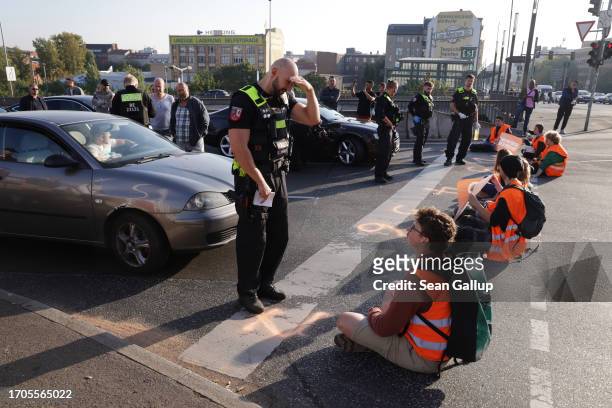 Police prepare to remove climate activists from the group "Last Generation" who had glued themselves on the asphalt to block an intersection on an...
